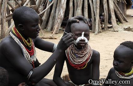 Karo woman painting a boy's face